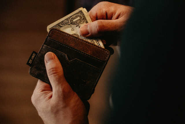 picture of hands pulling a dollar out of a wallet
