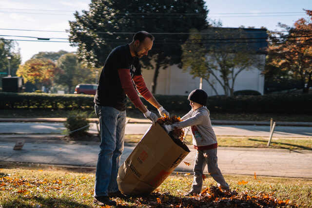 father and son picking up leaves