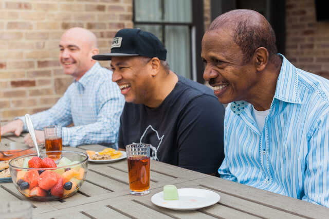 diverse group of men laughing around a table together