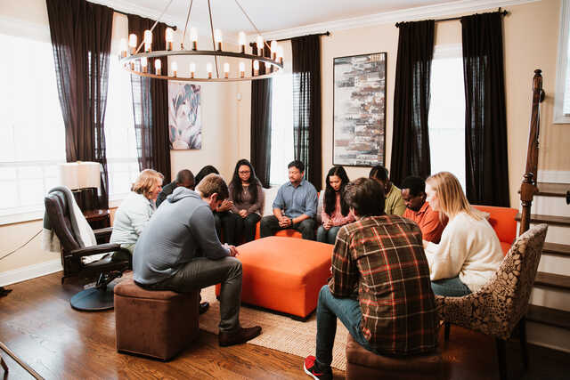 married small group meeting in a living room praying together