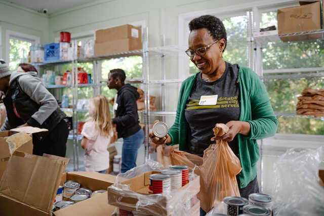 woman wearing a decatur city serves shirt sorting food at a pantry
