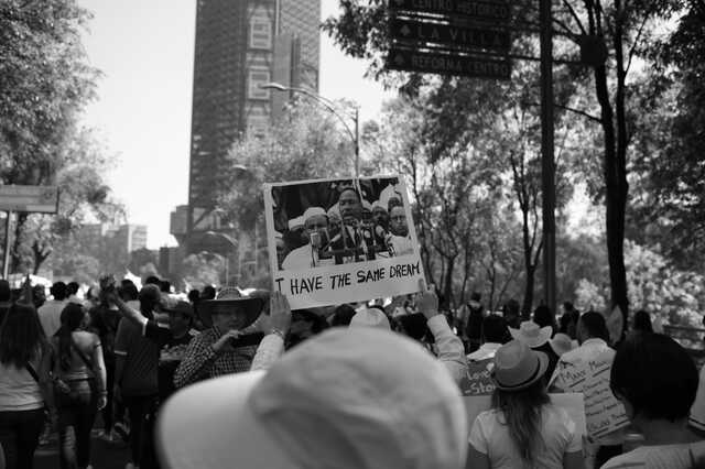 Black and white image of people gathered, holding up signs. 